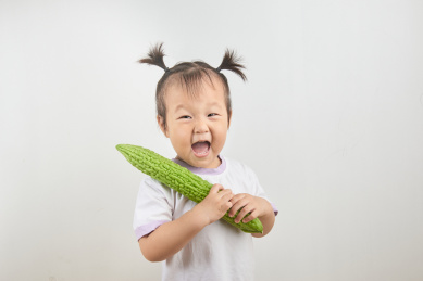 扎着小辫子的幼儿手捧一根苦瓜