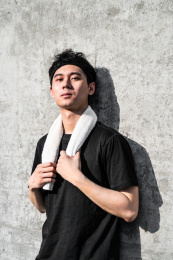 运动男子手抓毛巾靠墙休息发呆