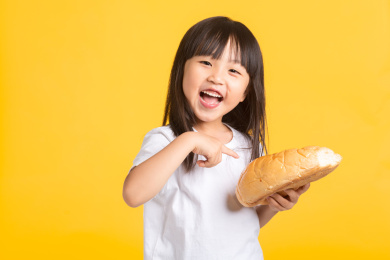 可爱的亚洲小女孩开心的指着手中的面包