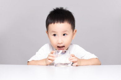 一个机灵可爱的小男孩在桌子前喝牛奶