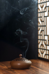 焚香的香炉佛珠线装书摆放在中式木桌面上