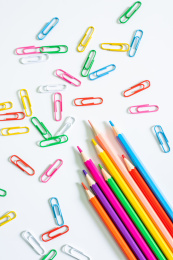 白底上几根彩色铅笔和随意散落的回形针