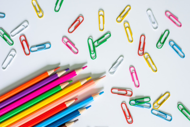 白底上几根彩色铅笔和随意散落的回形针