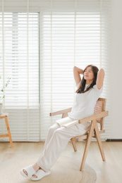 女生坐在百叶窗边的椅子上双手抱头闭眼休息