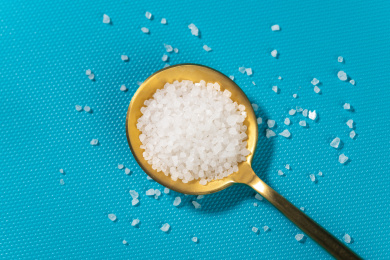 一勺食盐摆放在蓝色背景上特写