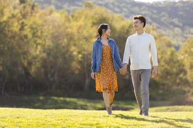 快乐的年轻情侣手牵手在草地上散步