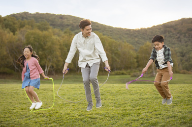 快乐的家庭在草地上比赛跳绳