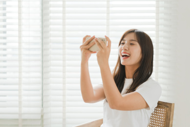 女生在窗边使用手机玩游戏