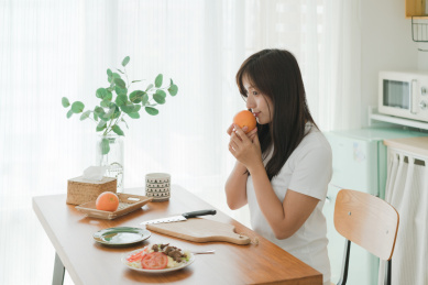 女生坐在厨房手拿橙子