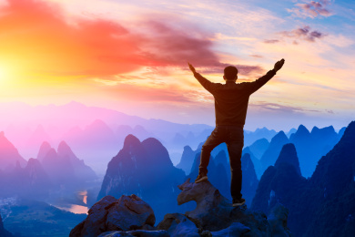 夏季日出时站在山上欣赏大自然的年轻人