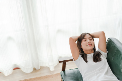 闭着眼睛的长发美女躺在沙发上快乐的笑着