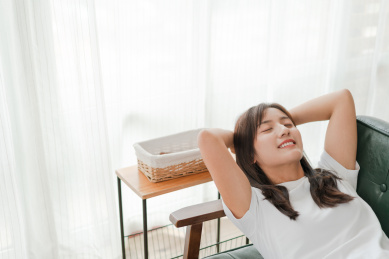 闭着眼睛的长发美女躺在沙发上快乐的笑着