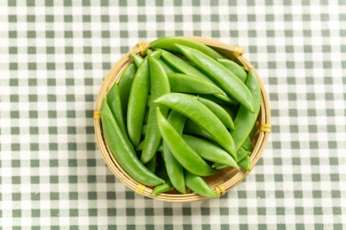 一簸箕甜豆摆放在格子桌布上
