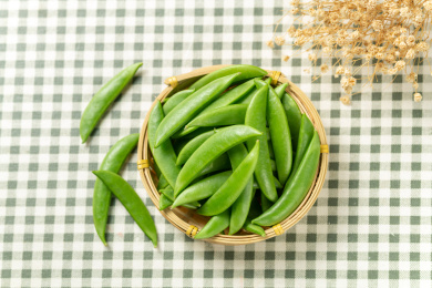 一簸箕甜豆摆放在格子桌布上