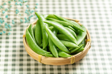 一簸箕甜豆摆放在格子桌布上