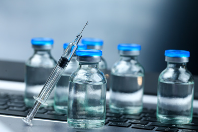 疫苗玻璃注射器和放在笔记本电脑键盘背景上