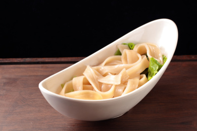 木桌上白盘里的重庆火锅菜品宽土豆粉