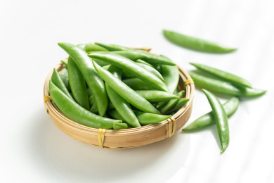 一簸箕甜豆摆放在白色背景上