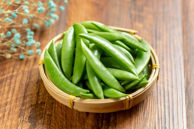 一簸箕甜豆摆放在木桌面上