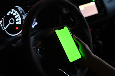 手拿着绿屏的手机在夜晚的汽车里