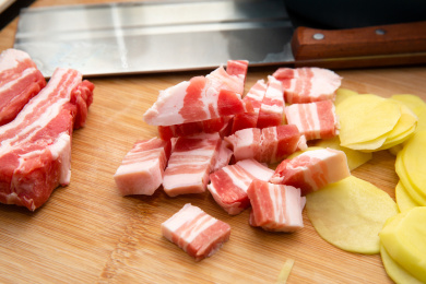 砧板上放着刚切好的土豆片和五花肉