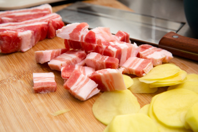 切好的猪五花和土豆片摆放在砧板上