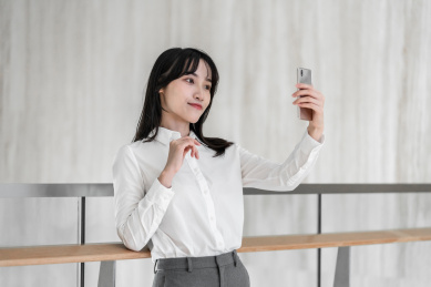 商务女性靠着栏杆用手机自拍