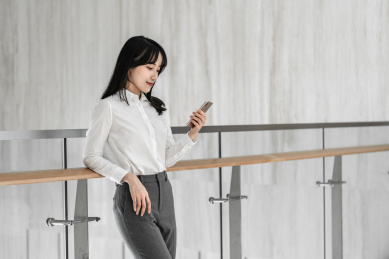 商务女性靠着栏杆使用手机