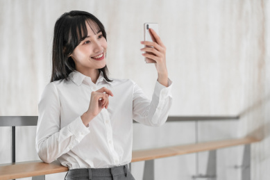 商务女性靠着栏杆用手机自拍