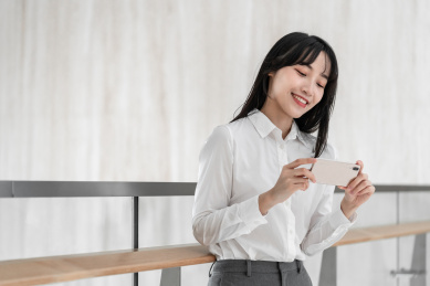 商务女性靠着栏杆使用手机拍照