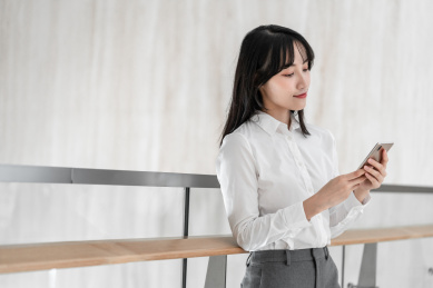 商务女性靠着栏杆使用手机