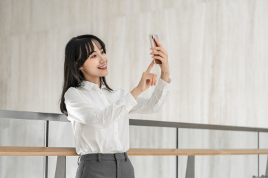 商务女性靠着栏杆用手机自拍