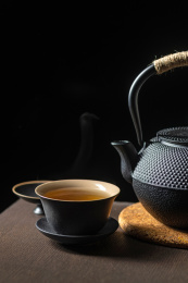 黑陶茶具三才杯盖碗与铁壶摆放在木桌面上