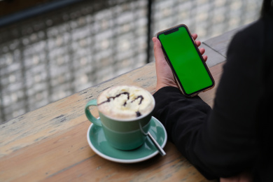 手拿着绿屏的手机在咖啡馆