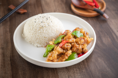 棕色木纹桌上放着一碗焦熘肉段盖饭