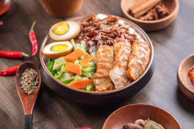 棕色木纹桌上放着一碗肉卷肥肠盖饭