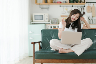 坐着沙发上使用笔记本视频通话的女人