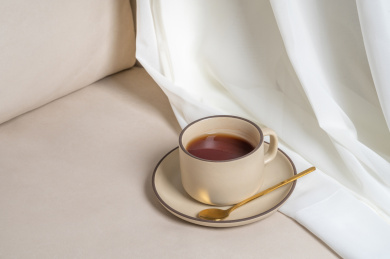 米色沙发上的一杯红茶和毛绒手套