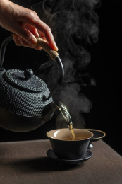 手持茶壶向盖碗中倒茶特写深色调