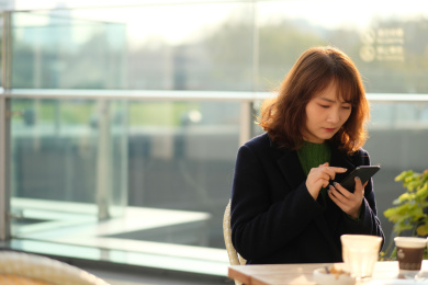 年轻的中国女子在户外阳光下使用手机