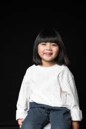坐在黑背景前玩耍的亚裔女孩