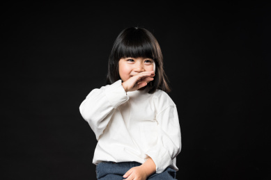 坐在黑背景前玩耍的亚裔女孩