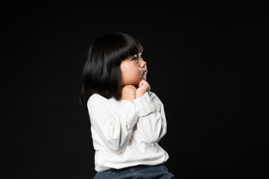 坐在黑背景前玩耍的亚裔女孩