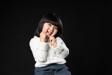 坐在黑背景前玩耍的亚裔女孩