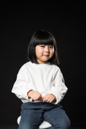 坐在黑背景前玩耍的亚裔女孩