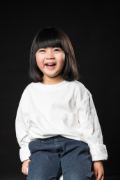 坐在黑背景前玩耍的亚裔女孩