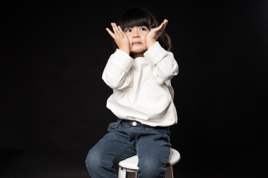 坐在黑背景前玩耍的亚裔女孩