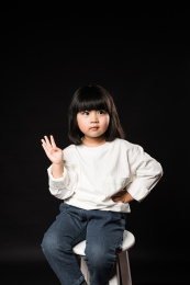 坐在黑背景前玩耍的亚裔女孩