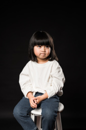 坐在黑背景前玩耍的亚裔女孩