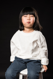 坐在黑背景前玩耍的亚裔女孩